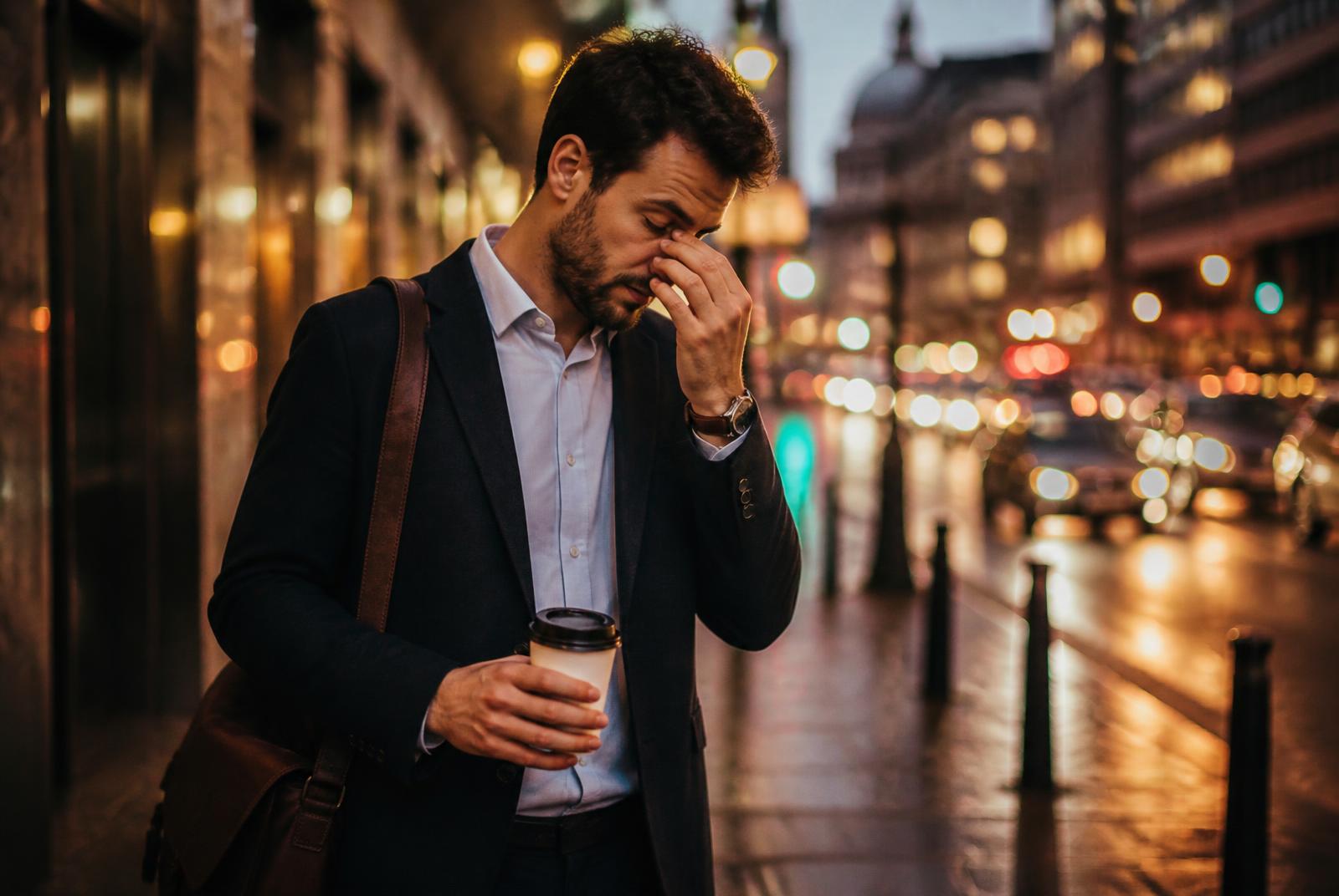 Commuter standing beside evening city traffic after a long day